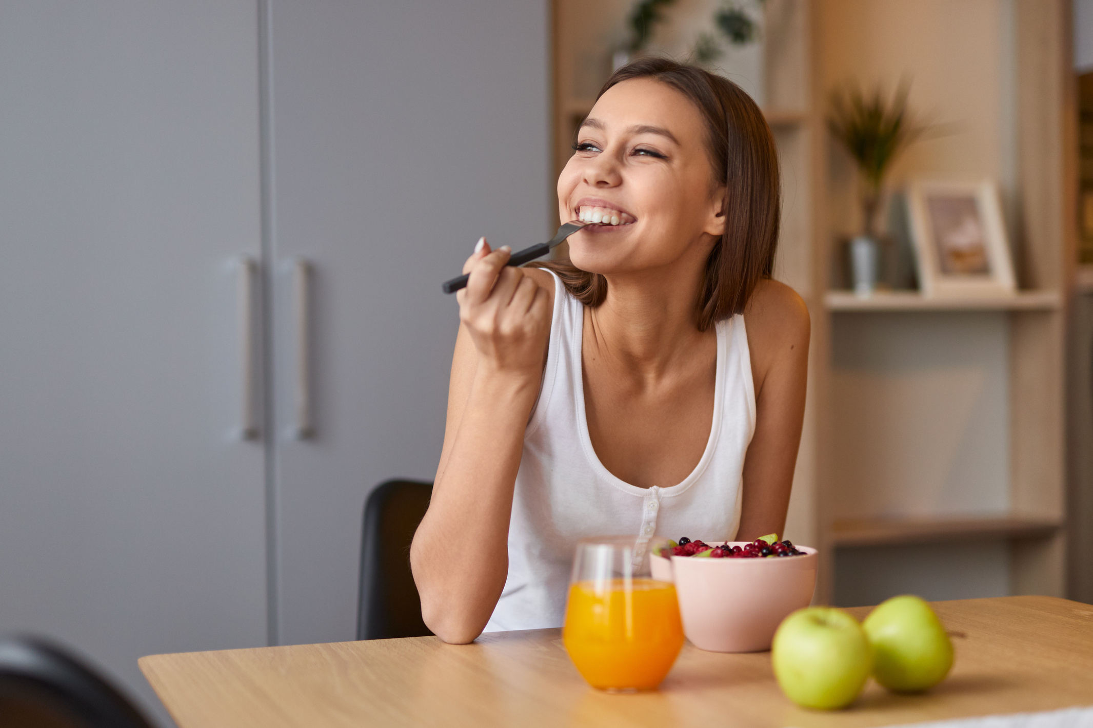 Happy woman eating healthy food during breakfast
